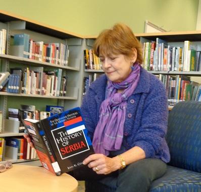 Linda, one of the visiting alumna, flips through a book on Serbian history in the new library. 