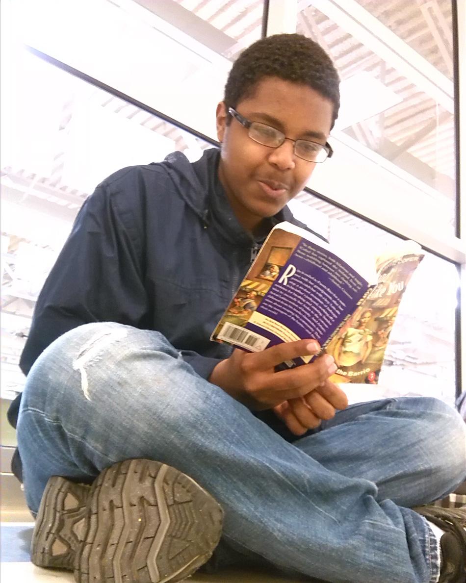 Senior Isaias Ogbe reads while he is criss cross apple sauce before school starts. 
