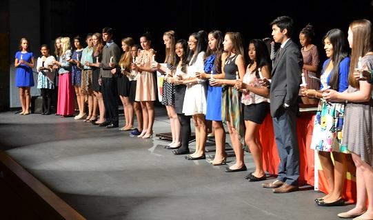 All the new inductees stand on stage with their lit candles. 