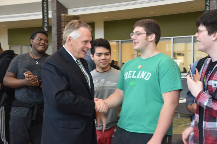 Senior Miles Kerby shakes the Governor's hand as he walks to the library. 