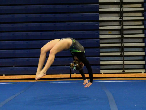 Gabby Spranger does a back hand spring on floor. 