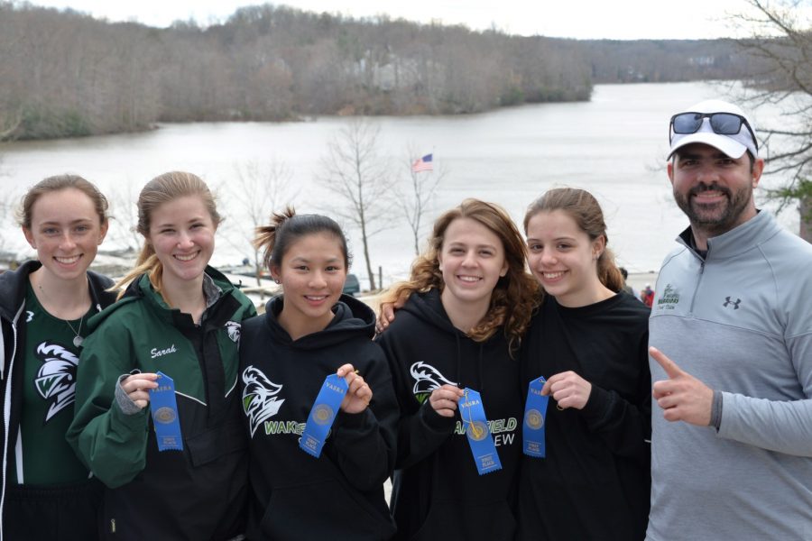 The Womens Lightweight Four posing with their first place ribbons and Coach James Augone.