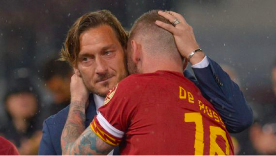 Totti hugging former Roman captain De Rossi.