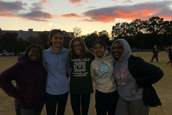 Cayla, Tara, Charlotte, Murchana, and Farah smile as the sun sets behind them on another great game.